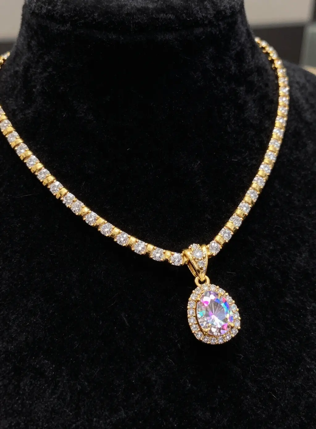 A gold riviera necklace with a pear-cut pendant on dark velvet.